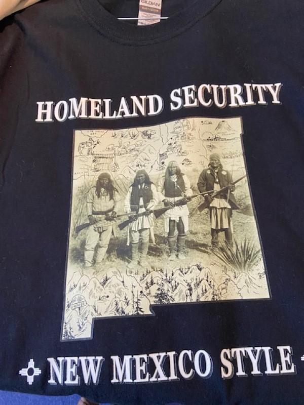 Homeland Security, New Mexico Style Black T-Shirt with New Mexico State Outline and Indigenous Men With Rifles